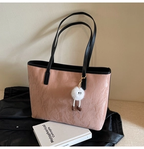Pink tote bag with pleated texture and plush charm in a cozy lifestyle setting