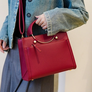 Elegant red leather handbag with round gold handles and shoulder strap for women