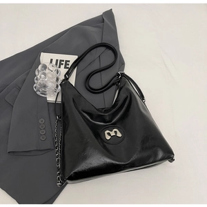 Detail of black large capacity hobo bag with silver metal M logo and chain decoration
