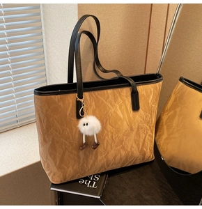 Close-up of khaki wrinkled texture tote bag with plush charm and black handles