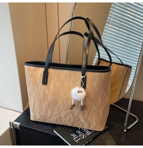 Detail of khaki tote bag with crinkle texture and cute plush doll charm accessory