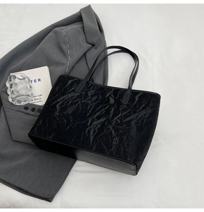 Detail view of large black tote bag featuring unique pleated texture and smooth handles