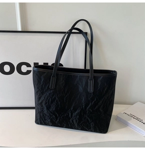 Detailed view of the black tote bag showing its unique wrinkled texture and smooth finish