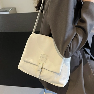 Cream white vintage tote bag with gold buckle on a model wearing a grey blazer