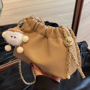 Chic beige ruched cloud bag with gold chain strap and cute plush monster charm