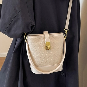 Sac seau beige chic avec texture tissée et fermoir doré porté sur une bandoulière