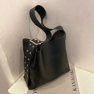 Sac seau minimaliste noir en similicuir avec large bandoulière à œillets dorés