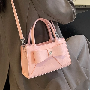 Pink crossbody handbag with large bow and heart crystal on minimalist autumn outfit