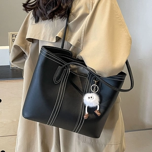 Classic black leather tote bag with white contrast stitching and plush doll charm