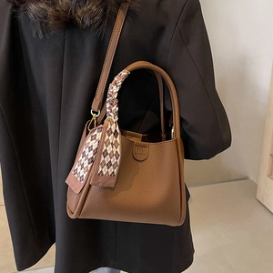 Classic brown leather bucket bag with silk scarf handle detail and long shoulder strap