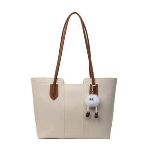 Chic cream and brown leather tote bag with unique plush doll charm and vertical stitching
