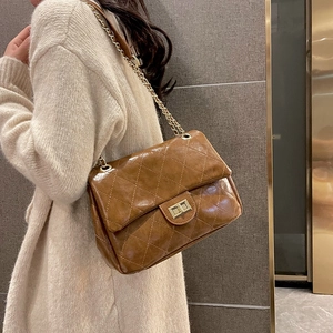 Brown quilted leather flap bag with gold chain strap worn by a model in a warm setting