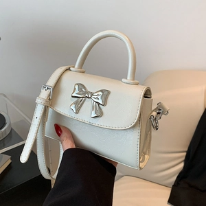 Creamy white ruched leather crossbody bag with silver bow accent and top handle