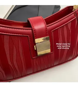 Detail of red wedding handbag featuring golden rectangular metal buckle and wave-texture leather