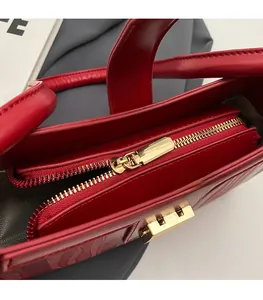 Detail of red bridal handbag showing golden metal zipper and wavy embossed leather texture
