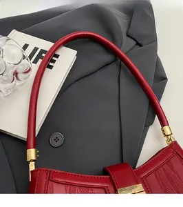 Detail of red embossed leather handbag with golden clasp and round shoulder strap