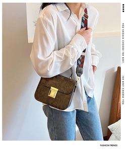 Detail of vintage brown textured crossbody bag with gold square buckle and colorful strap