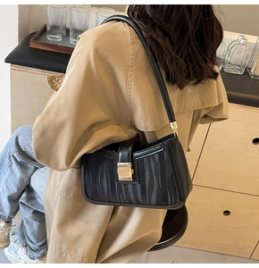 Close-up of elegant black mesh shoulder bag with golden lock and vertical texture