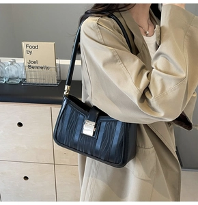 Chic black rectangular shoulder bag with vertical wave texture and gold buckle on a model