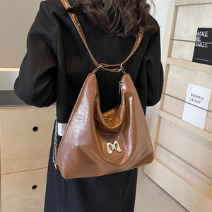 Brown vintage wrinkled leather hobo bag with silver M logo shown in a lifestyle setting