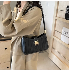 Detail of minimalist black leather handbag with wavy texture and gold metal buckle