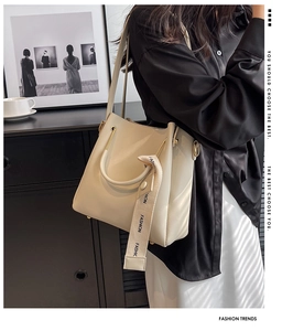 Detail view of large beige bucket bag with fashion strap and golden metal eyelets