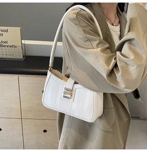 Chic white shoulder bag with wave texture and gold hardware worn by model