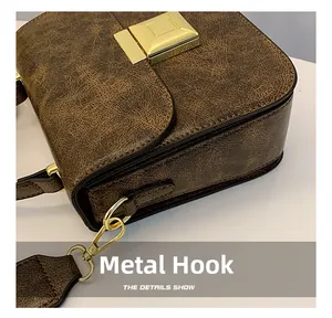 Close-up of golden hardware hooks and vintage textured leather on a brown crossbody bag