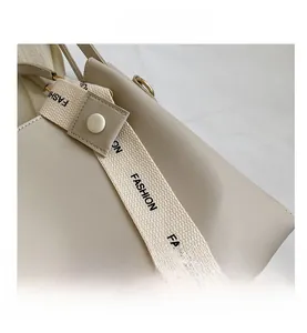Detail of cream leather bucket bag with fashion woven strap and gold metal hardware