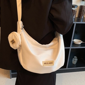 Sac bandoulière demi-lune blanc avec petit porte-monnaie sur un mannequin en tailleur