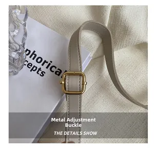 Close-up of polished gold metal adjustment buckle on beige leather crossbody strap