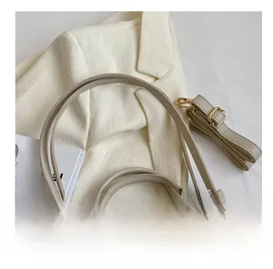 Close-up of beige leather bucket bag with top handle and decorative FASHION strap