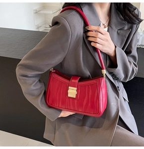 Close-up of red wedding handbag with wave texture on a model in a grey blazer