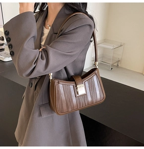 Detail of vintage brown shoulder bag with vertical wavy texture and gold metal buckle