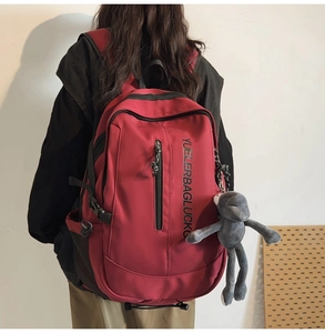 Macro detail of deep red large capacity backpack with letter print and plush monkey charm