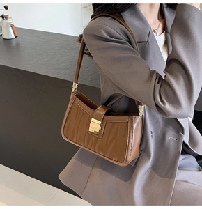 Brown vintage underarm bag with animal texture and gold clasp worn over a taupe blazer