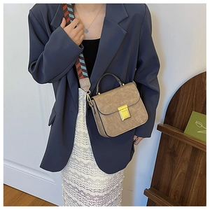 Detail of vintage brown crossbody bag featuring ethnic style wide woven shoulder strap