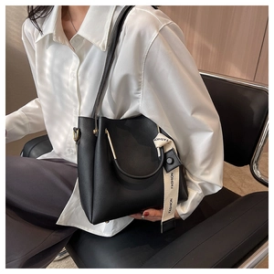 Detail of black leather bucket bag with gold metal handle and fashion strap accessory