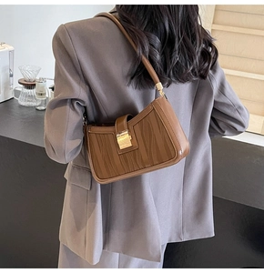 Brown vintage baguette bag with wave texture and gold buckle shown on shoulder