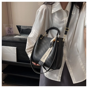 Detail of black large bucket bag with fashion print webbing and gold metal hardware