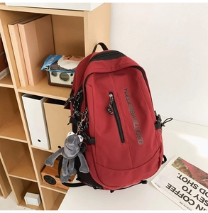 Close-up of deep red large capacity backpack with pockets and cute cartoon pendant