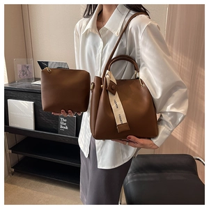 Detail of 2-in-1 brown leather bucket bag set featuring a chic 'FASHION' fabric ribbon