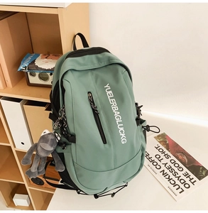Detail of mint green school backpack with side pockets and plush doll accessory