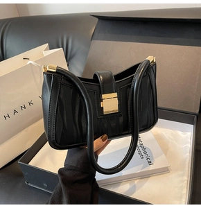 Detail of black textured PU leather handbag featuring a golden square metal lock and wave patterns