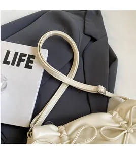 Detail of a creamy white leather shoulder bag with bow knot on a grey blazer