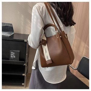 Brown leather bucket bag with fashion print strap shown in a modern lifestyle setting