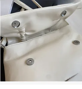 Detail of cream leather tote bag featuring magnetic closures and silver brand logo