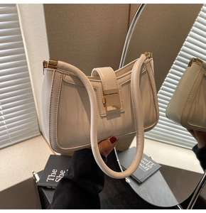 Close-up of off-white textured leather handbag featuring a premium gold metal buckle