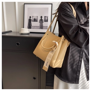 Detailed shot of yellow bucket bag featuring dual straps and fashion webbing accessory