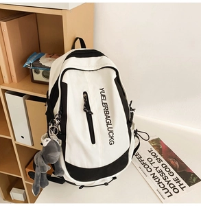 Detail showing the large capacity black and white backpack with a plush frog charm